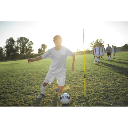 Soccer player dribbles ball during practice on grass field with teammates nearby