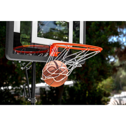 Basketball enters the hoop on an outdoor court during daytime