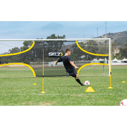 A soccer player practices goalkeeping skills with a portable goal on a field