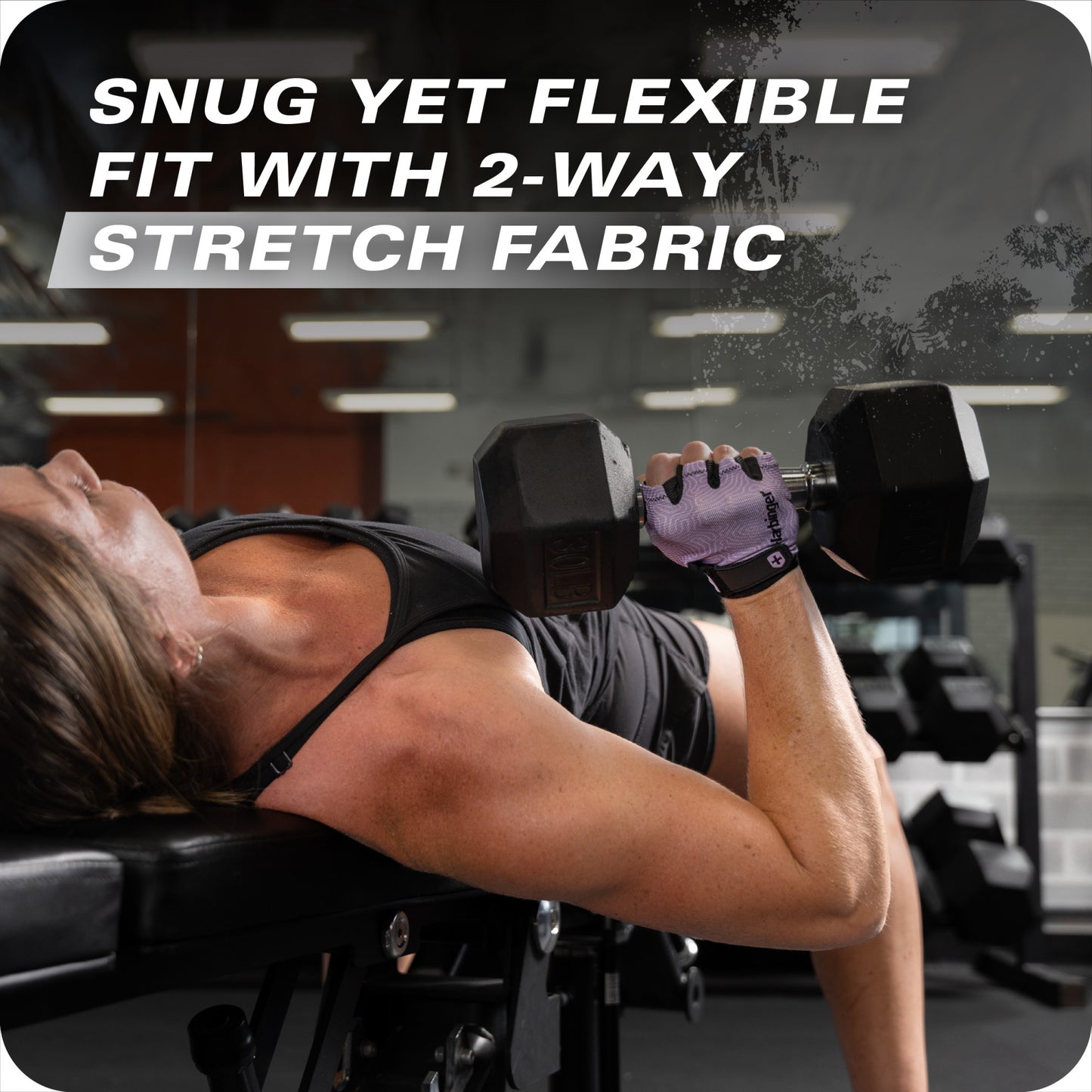 Woman performs dumbbell bench press on a workout bench in a gym using stretch fabric.