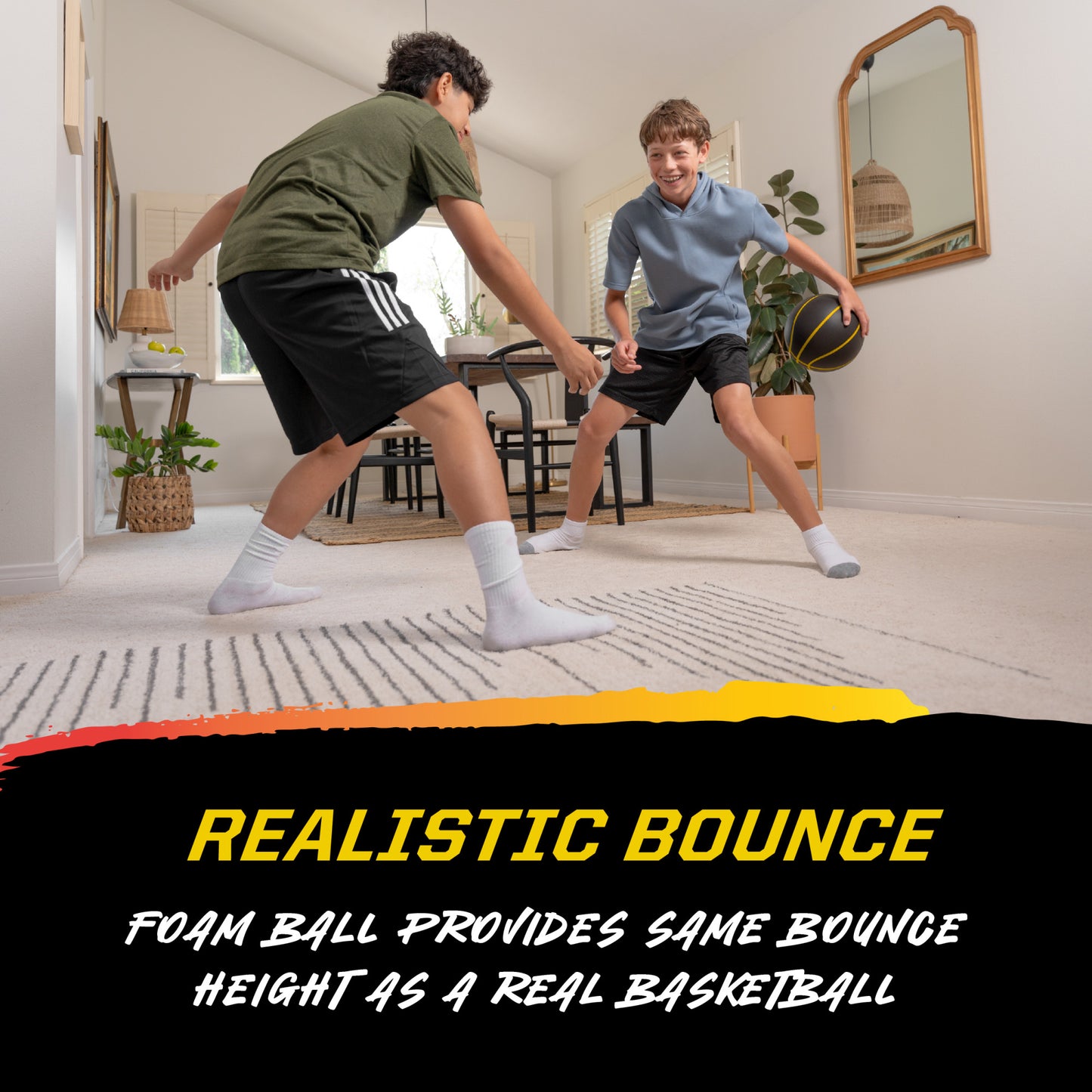 Kids playing with foam basketball on carpet in a bright living room with plants and a mirror.