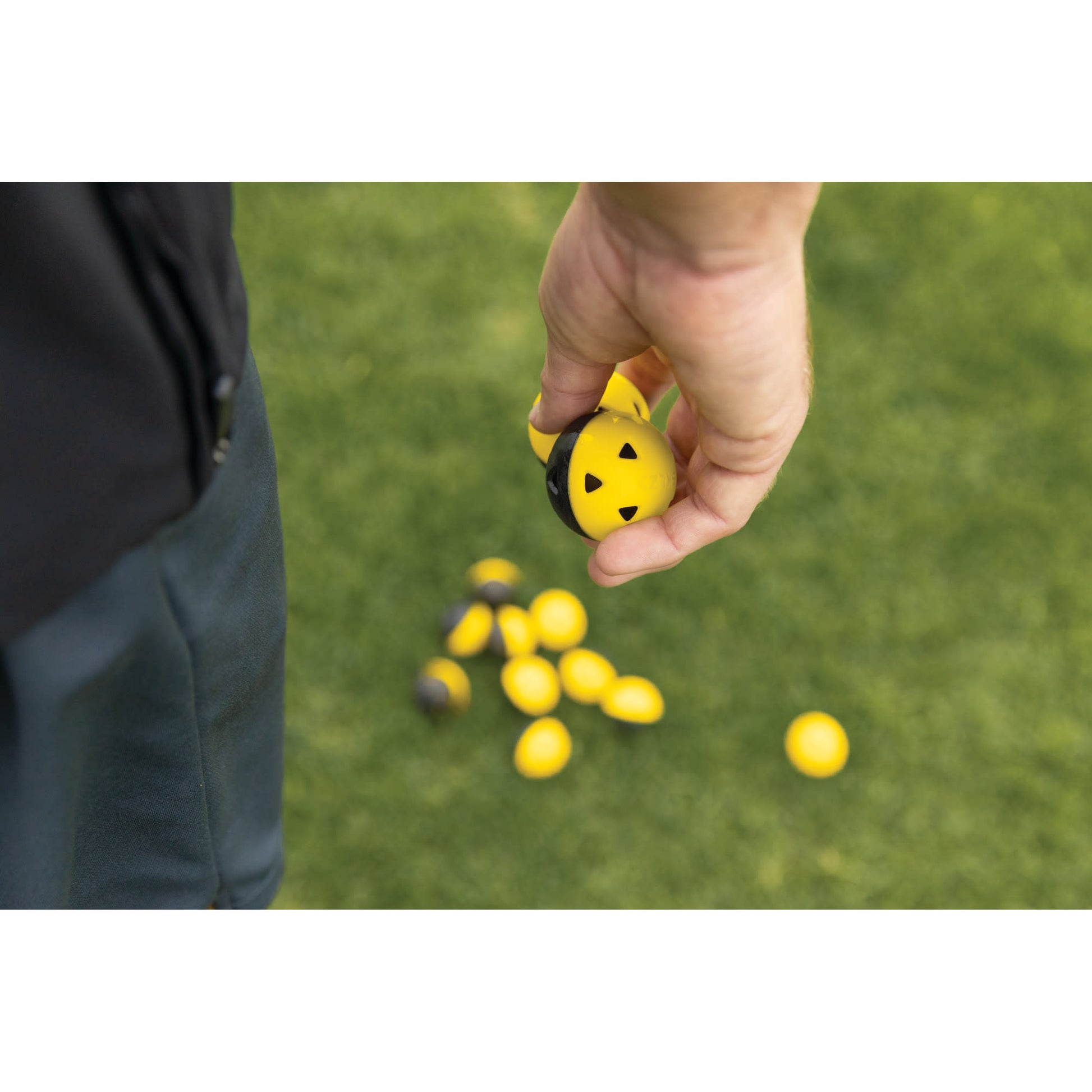 Hand drops yellow golf tee markers on a green field for marking a golf course