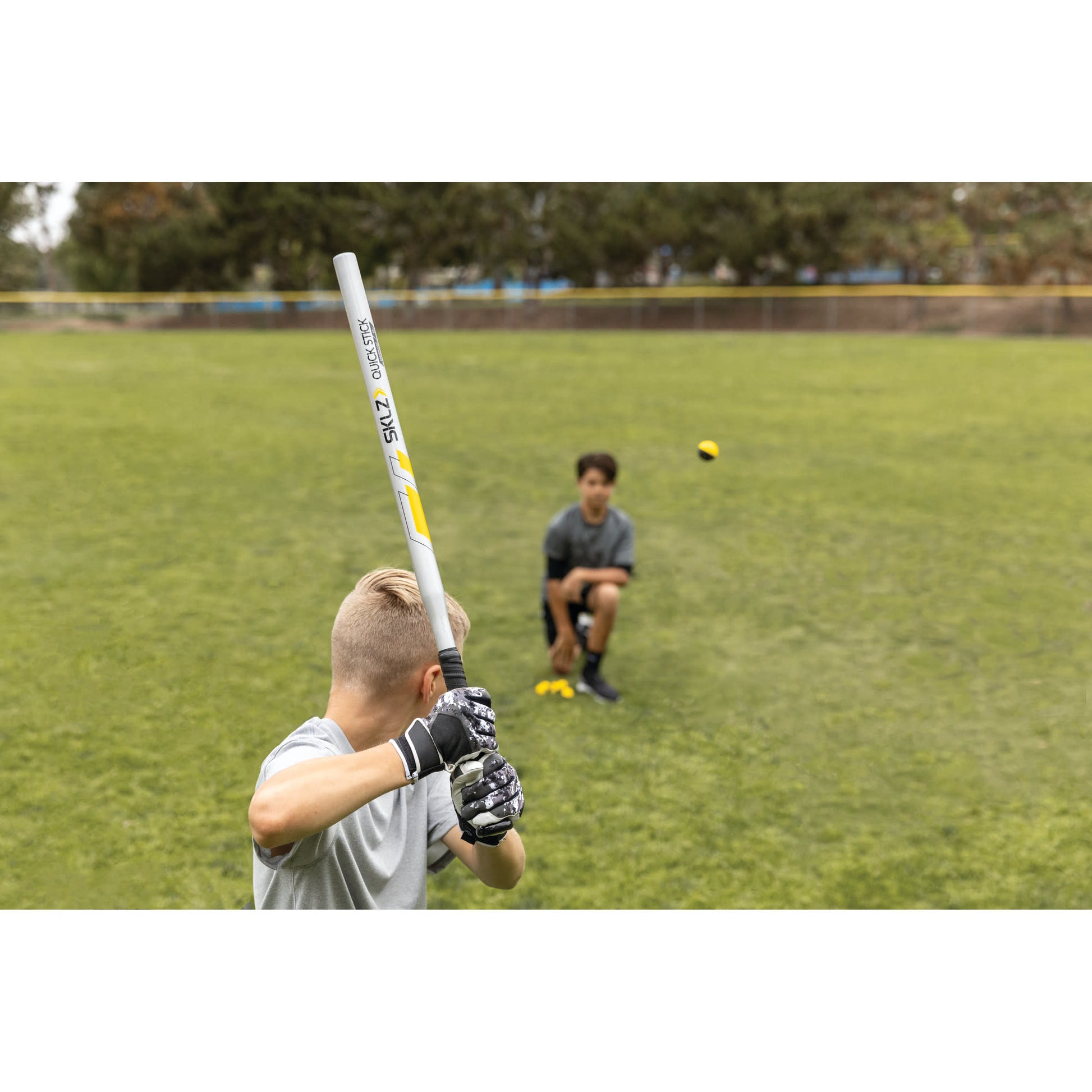 Boy practicing baseball with a bat on a grassy field during a training session