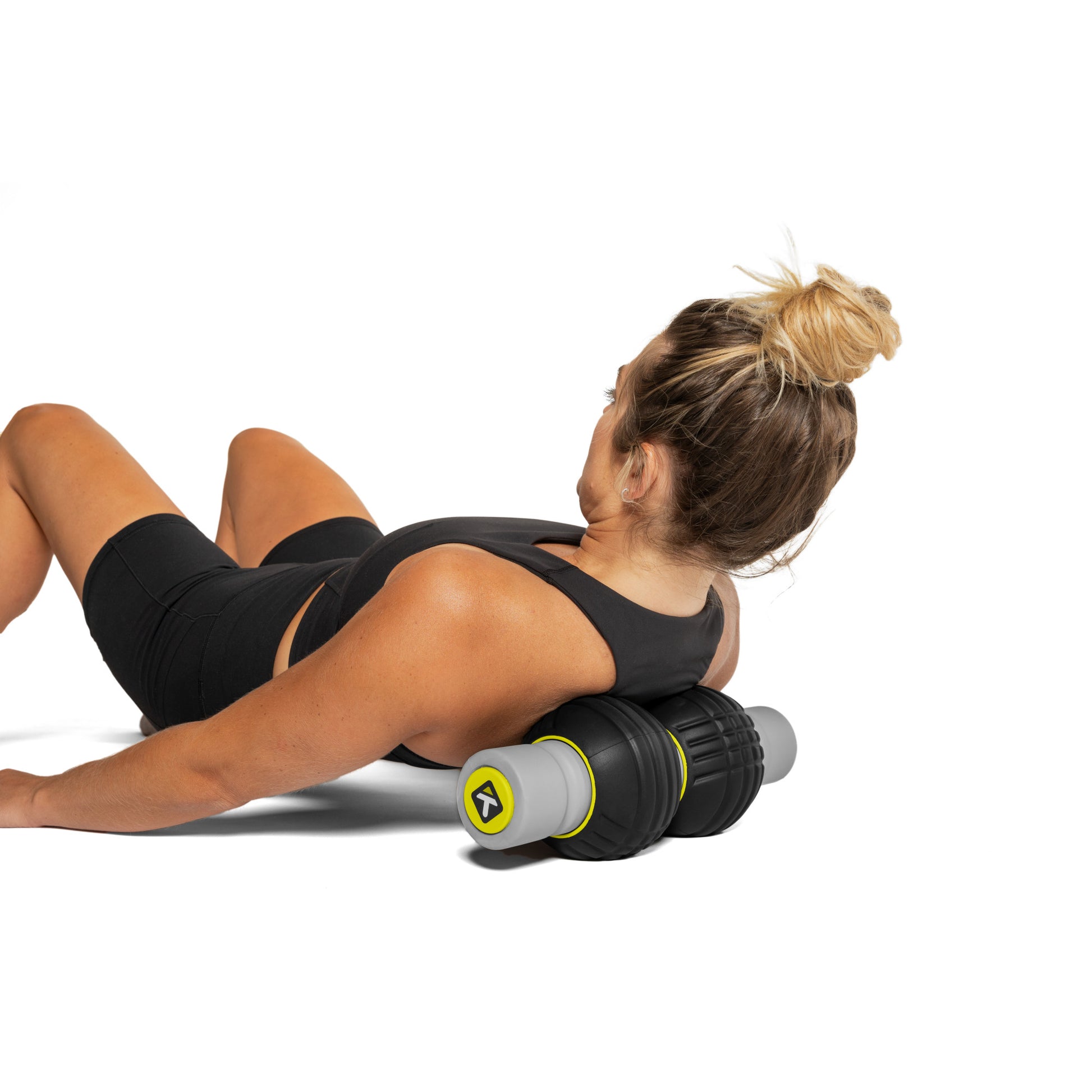 Woman performs abdominal exercise using foam roller on white background