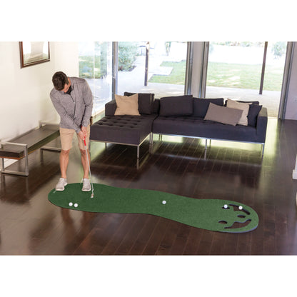 Person practicing golf putting on an indoor mat in a living room with a sofa and large windows