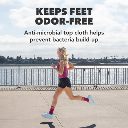 A woman runs outdoors near a body of water, wearing anti-microbial top cloths.