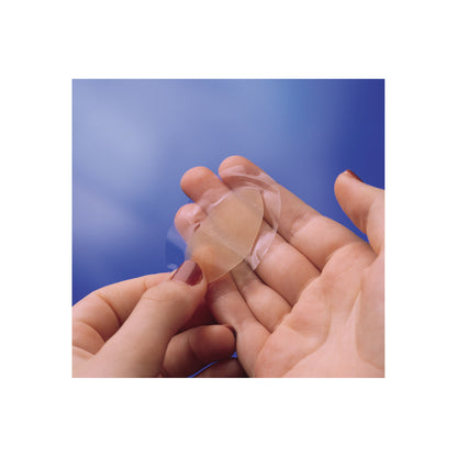 A person applies a transparent adhesive bandage to another person's finger against a blue background.