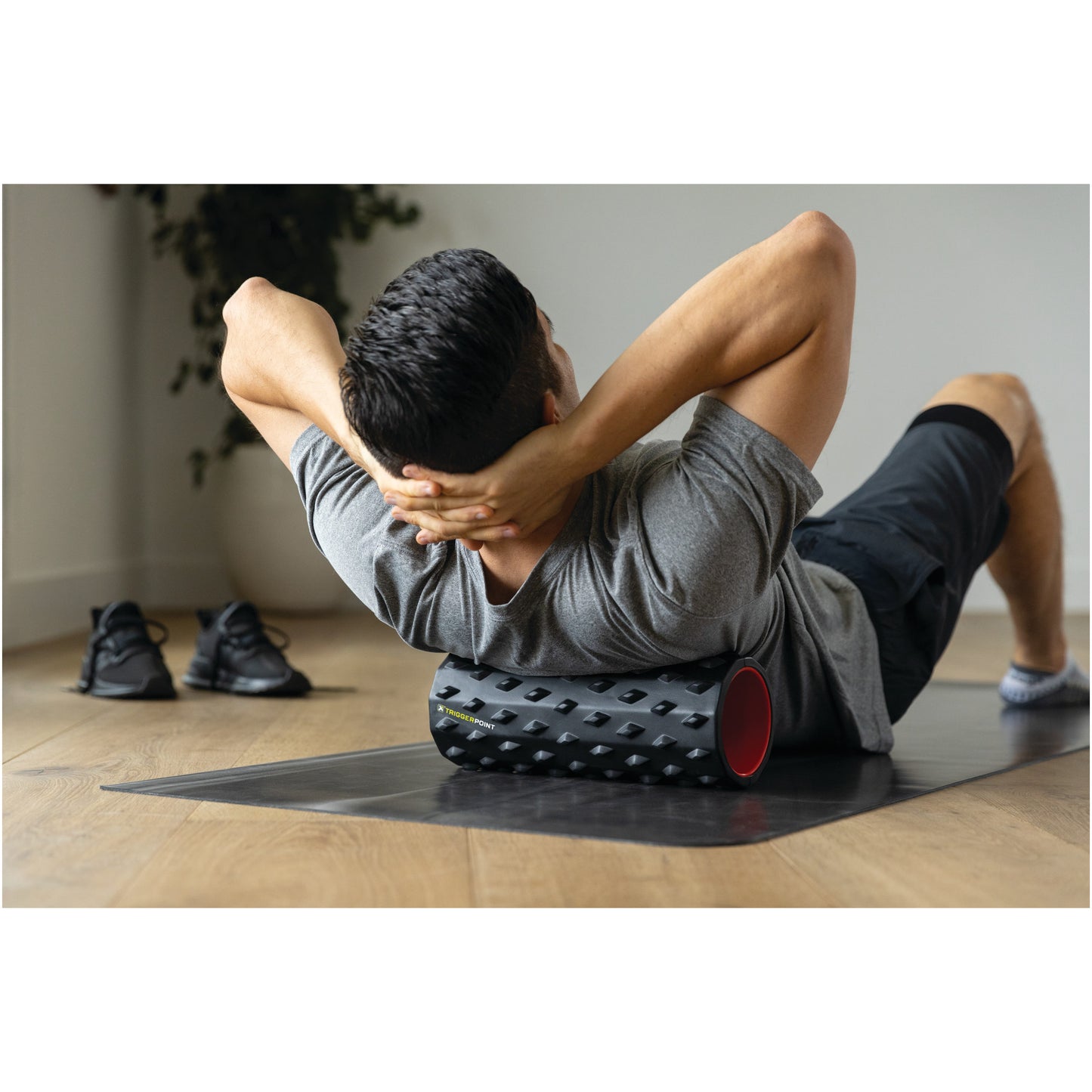 Person exercises on a foam roller to relieve muscle tension in a home gym setting.