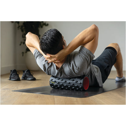 Person exercises on a foam roller to relieve muscle tension in a home gym setting.