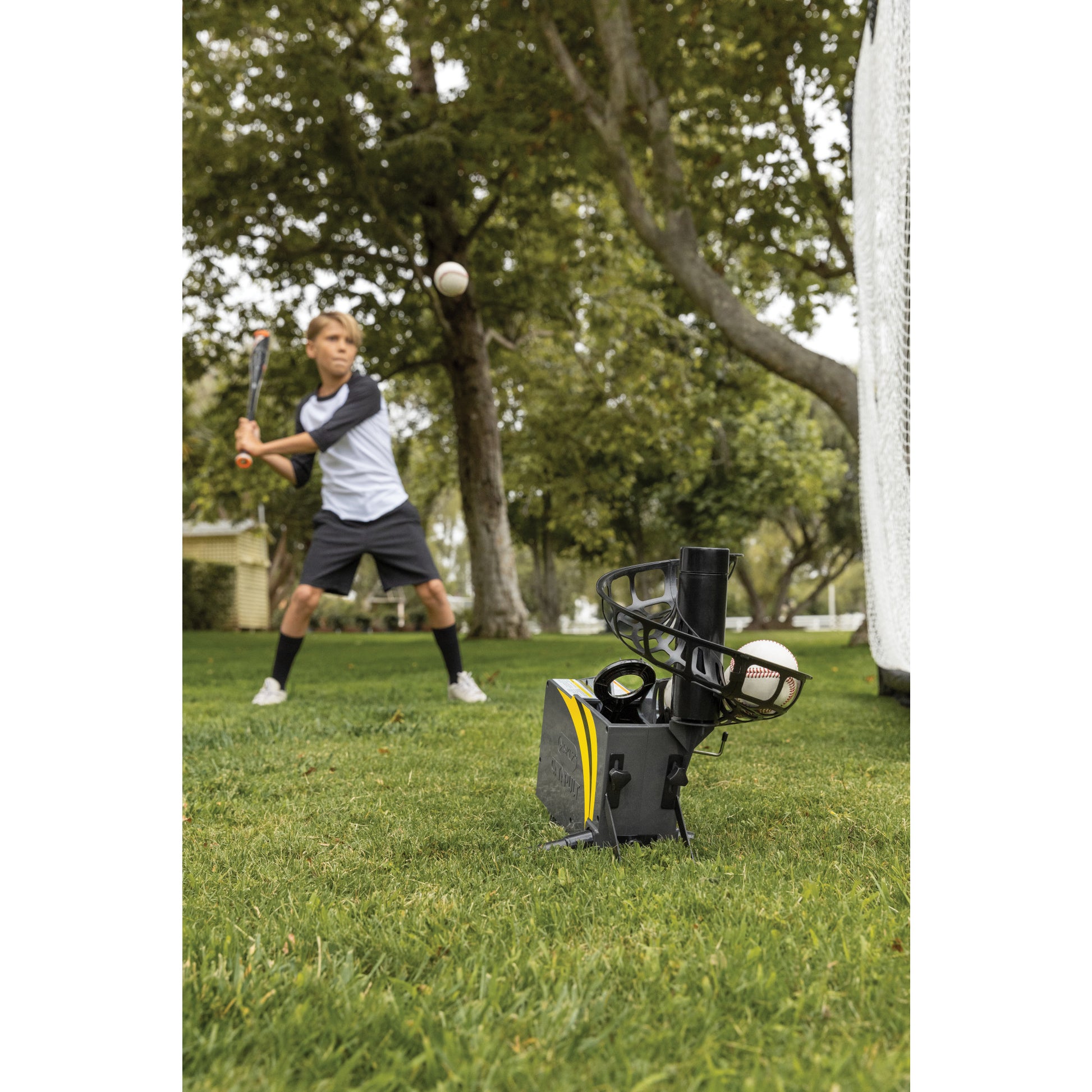 Boy practices baseball batting with a tee in a park during daytime