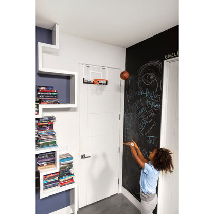 Child writes on blackboard in a room with books and a small basketball hoop