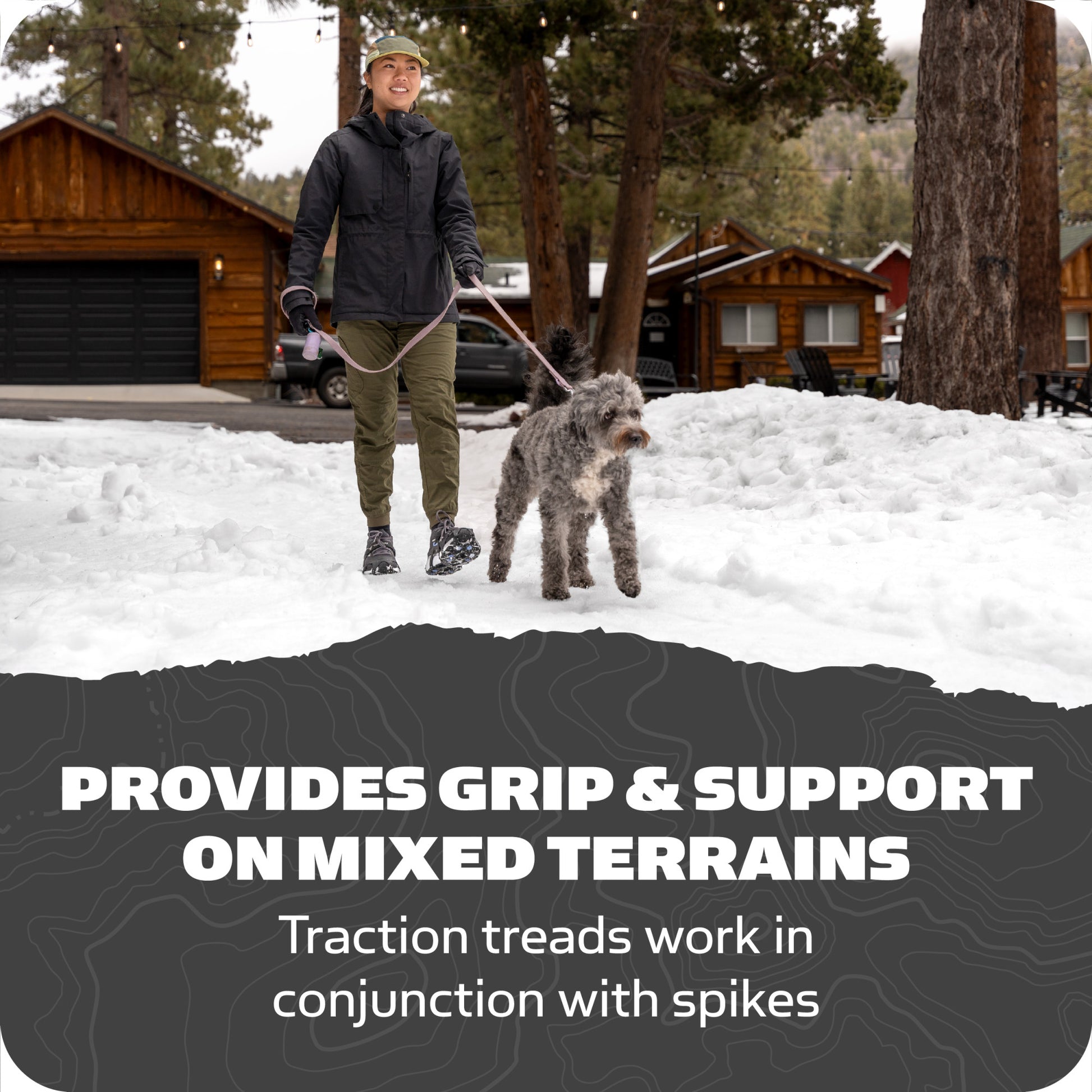 Person walks dog on snow near cabins and trees, promoting grip and support gear.