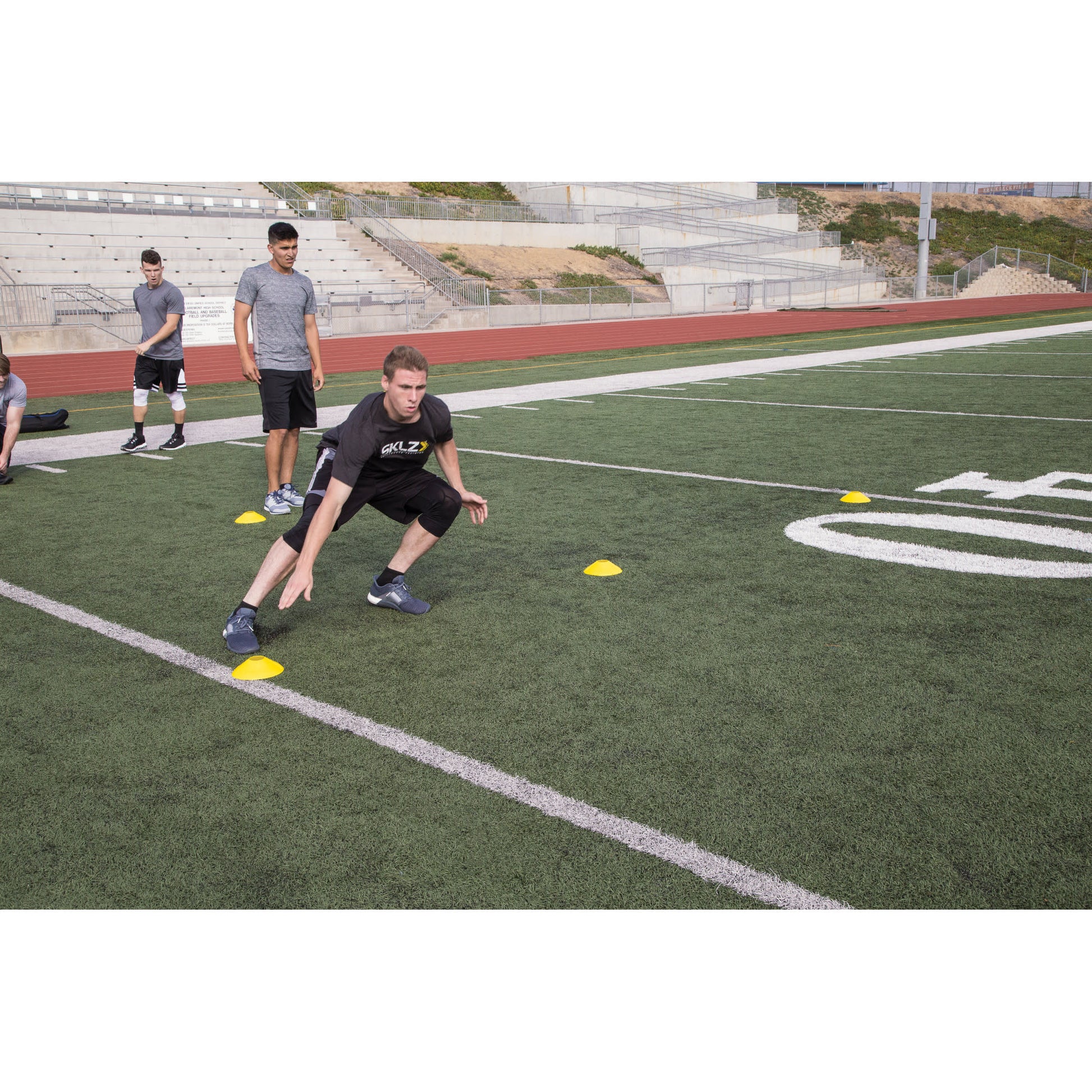 Athletes perform agility drills on a football field during practice session outdoors