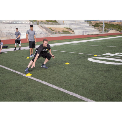 Athletes perform agility drills on a football field during practice session outdoors
