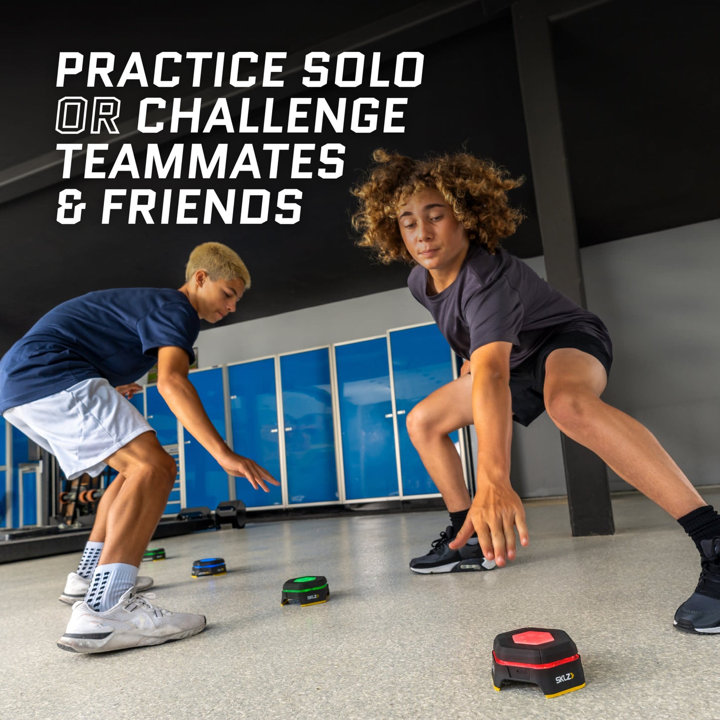 Two young people practice agility drills with small black and green devices in a gym