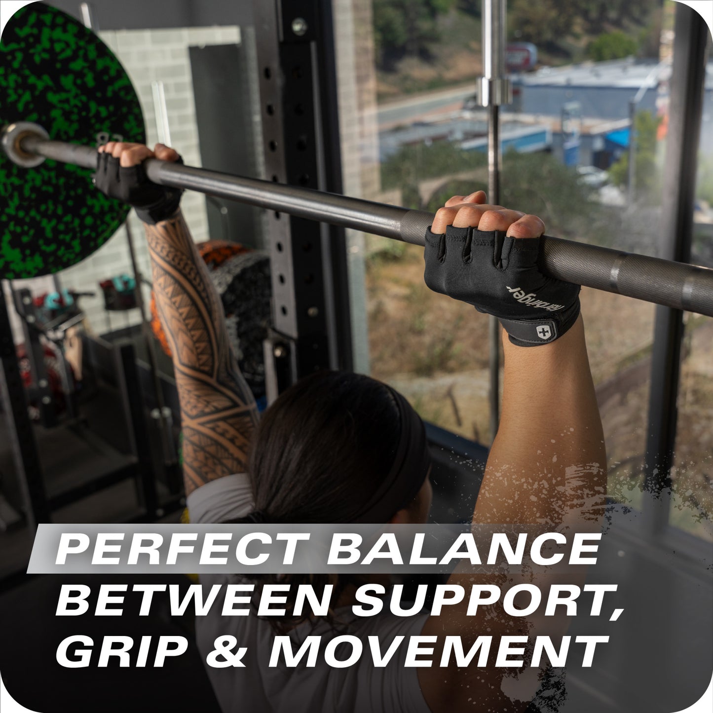 Person lifts a barbell for strength training in a gym with a city view behind.