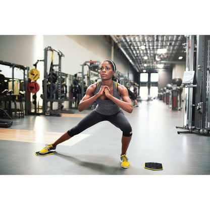 Woman exercises in gym lunges with a balance board on the floor