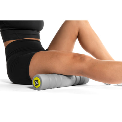 Person uses foam roller to massage thigh on white background