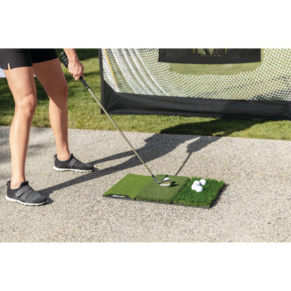 Person practicing golf swings on outdoor mat with golf balls