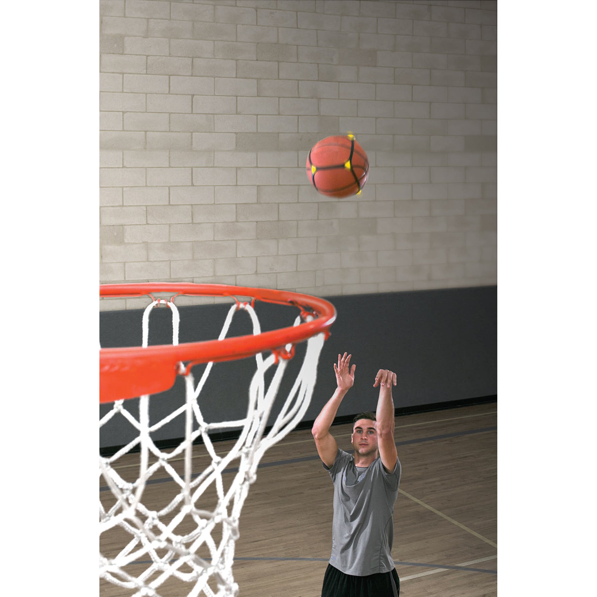 Basketball is shot by a player towards the hoop in an indoor gymnasium