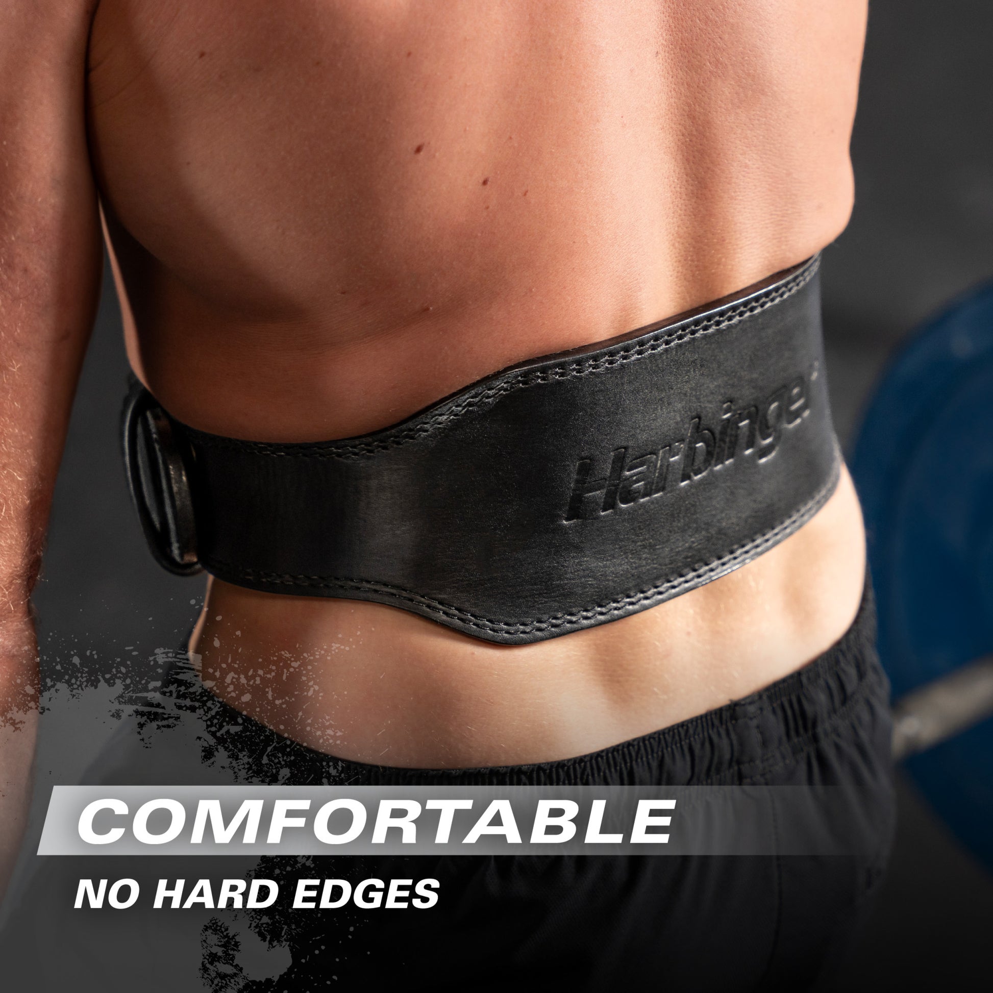 A person wears a black weight lifting belt around their waist in a gym setting.