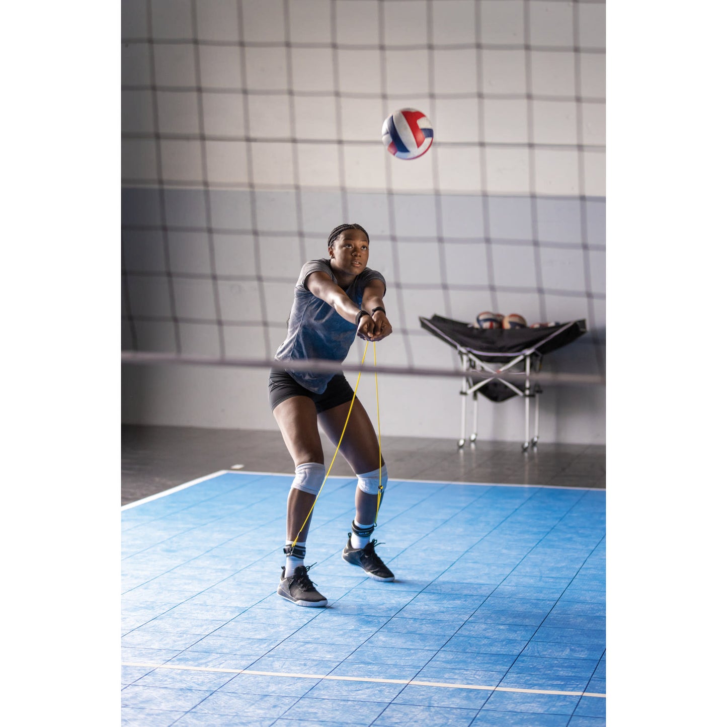 Female bumping volleyball while using SKLZ Bump and Pass trainer in a gym