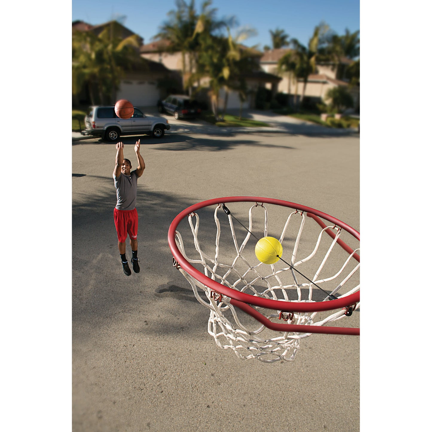Action shot of a male shooting a jump shot with a close-up shot of the SKLZ Basketball shooting target in the street