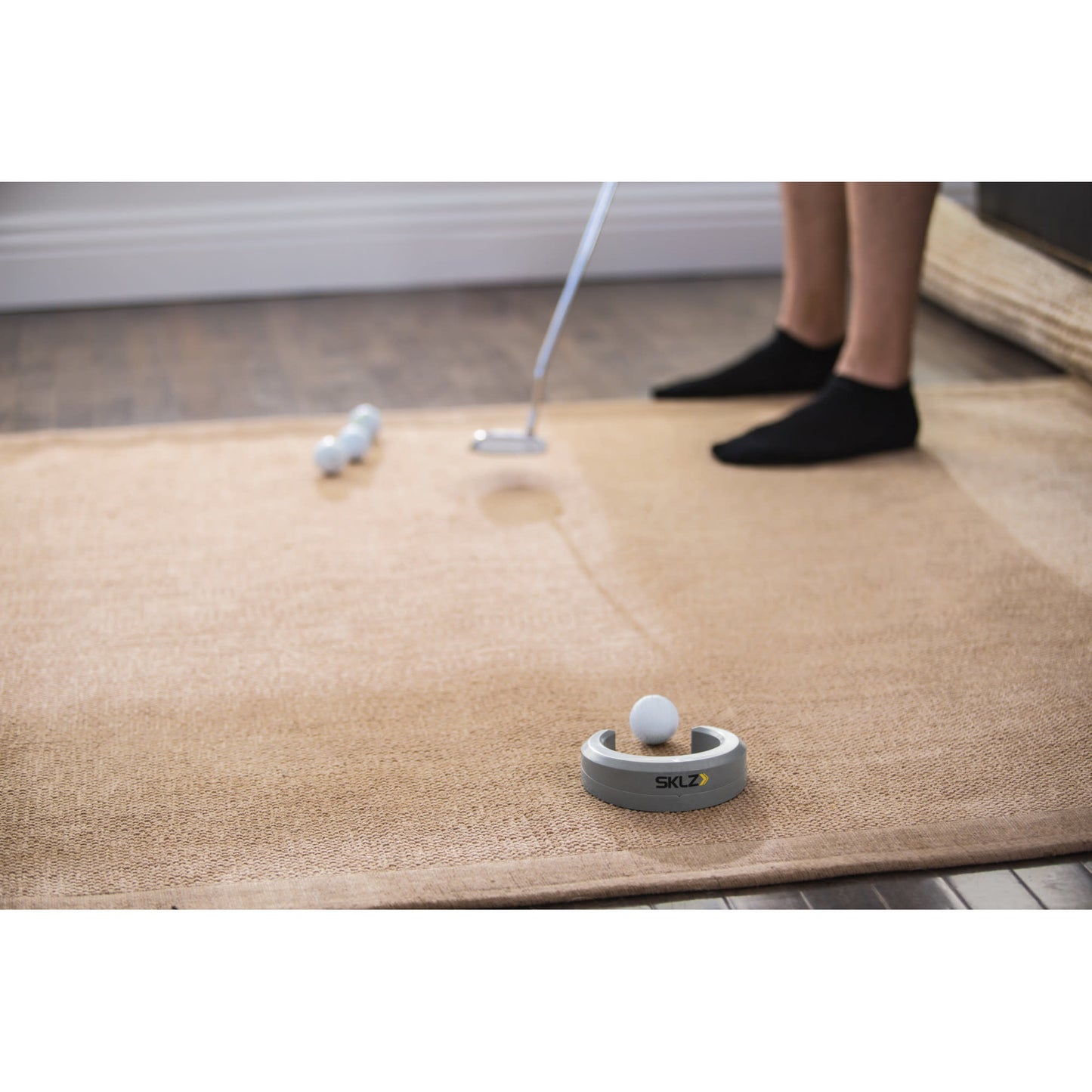 A robot golf ball collector retrieving balls on a beige rug indoors