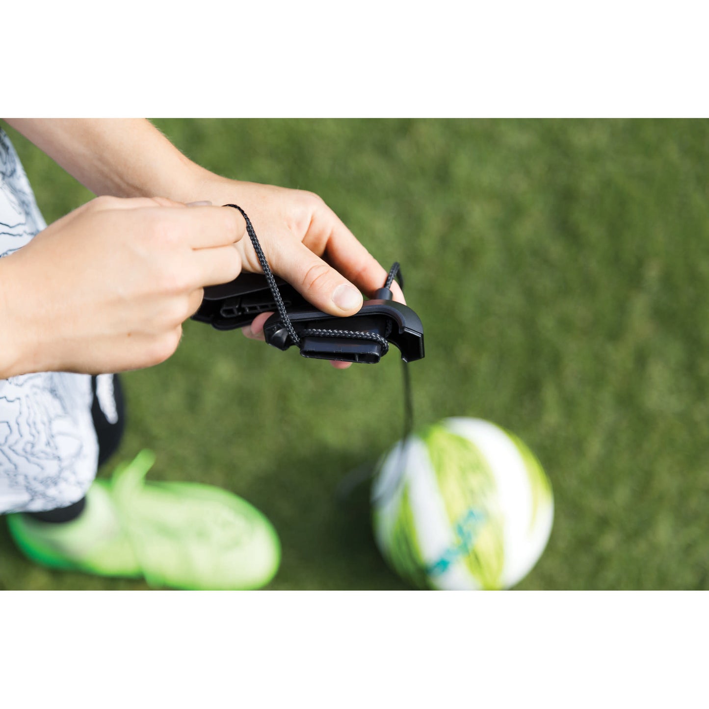 Person holds a stopwatch on a grassy field near a soccer ball