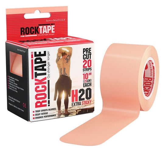 A roll of peach-colored athletic tape unrolled near its packaging on a white surface.