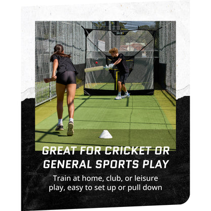 Two children practice cricket batting in a netted indoor cricket cage