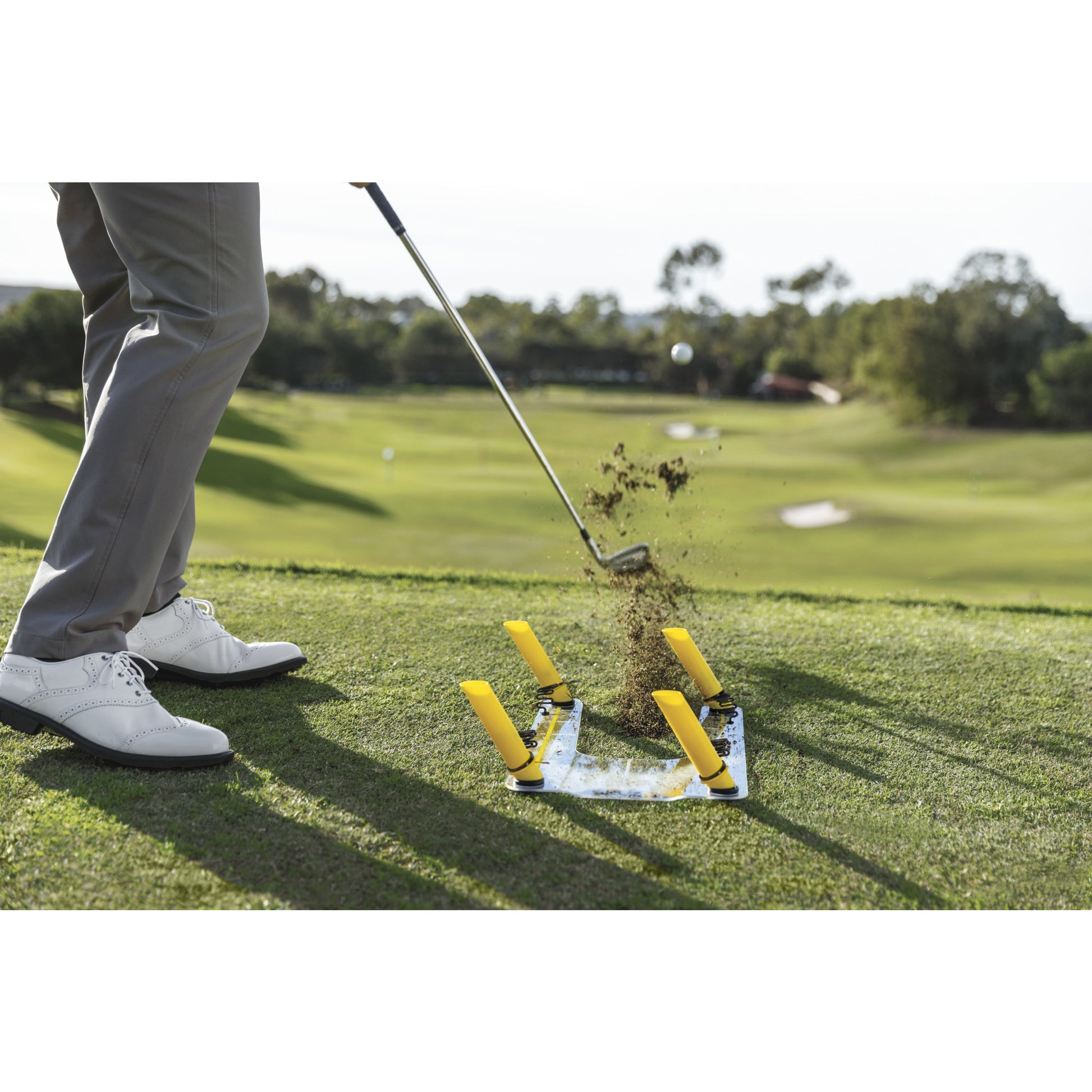 A person practices chipping on a golf course with a golf club and target markers