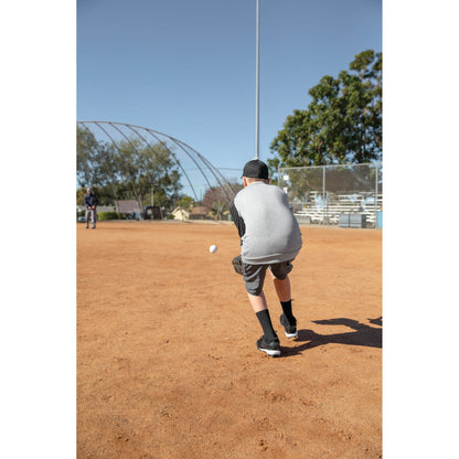Boy practicing catch on baseball field under clear sky