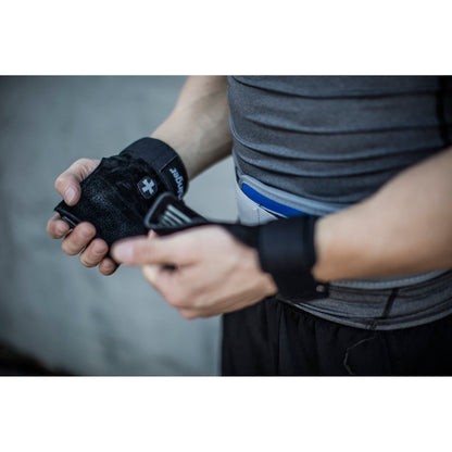 Person adjusts a fitness tracker on their wrist in a gym or fitness environment.