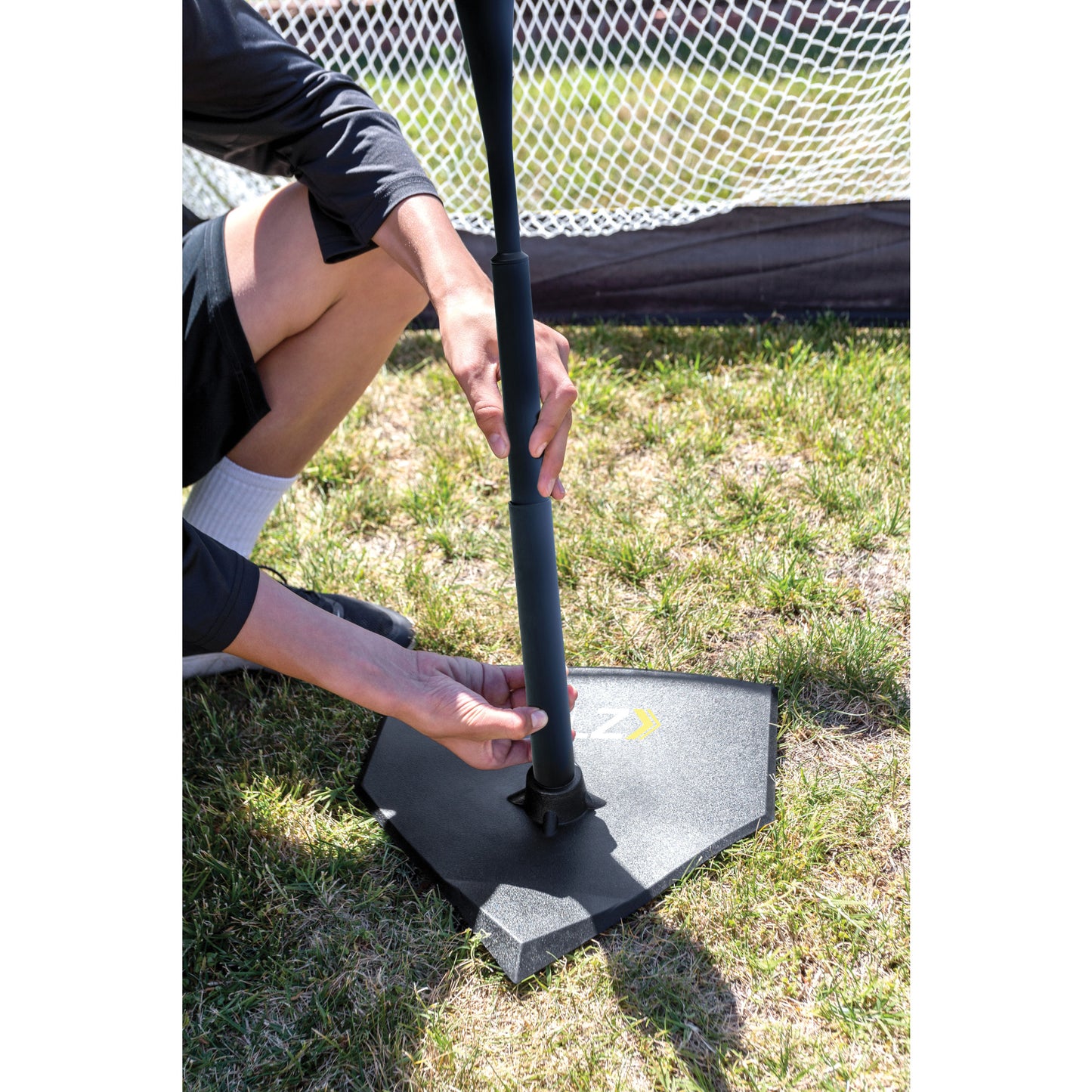 Person adjusts a portable soccer goal on grass field in an outdoor setting
