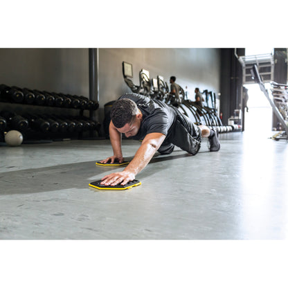 Man performs pushups with sliders on gym floor in a fitness center