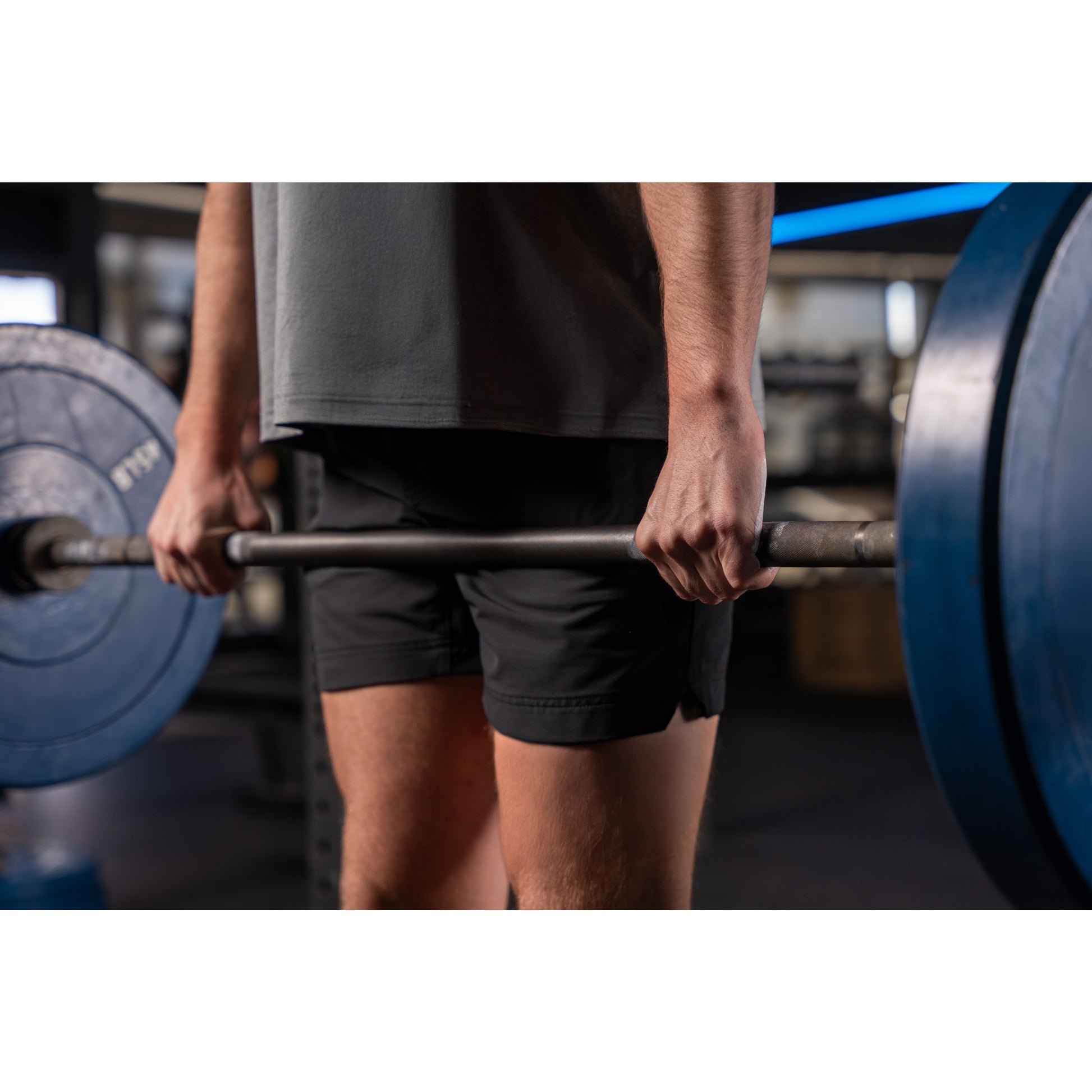 Person grips barbell weightlifting in a gym.