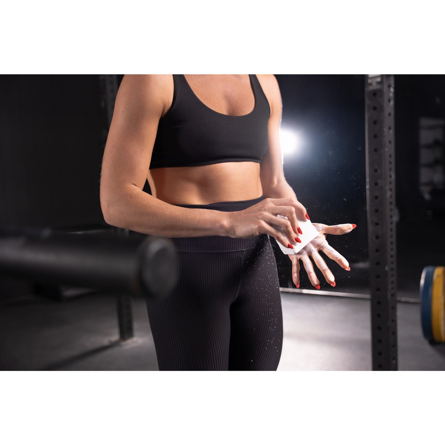 Athlete applies chalk on hands in a gym, preparing for lifting weights.