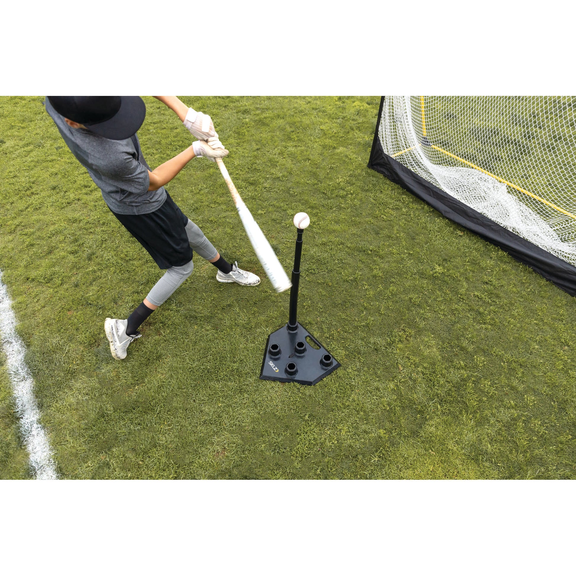 Overhead shot of youth male hitting off SKLZ 5-Position Tee on a field into a net