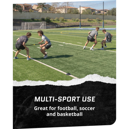 Four boys play tug of war on a green turf field in a sports complex