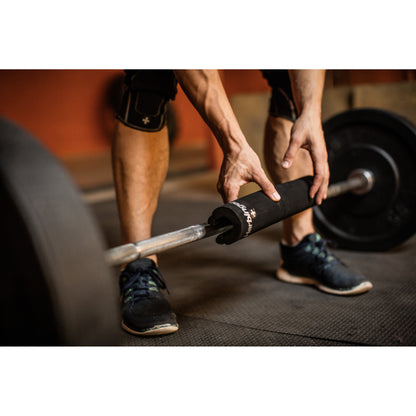 Hands grip weighted barbell on gym floor.