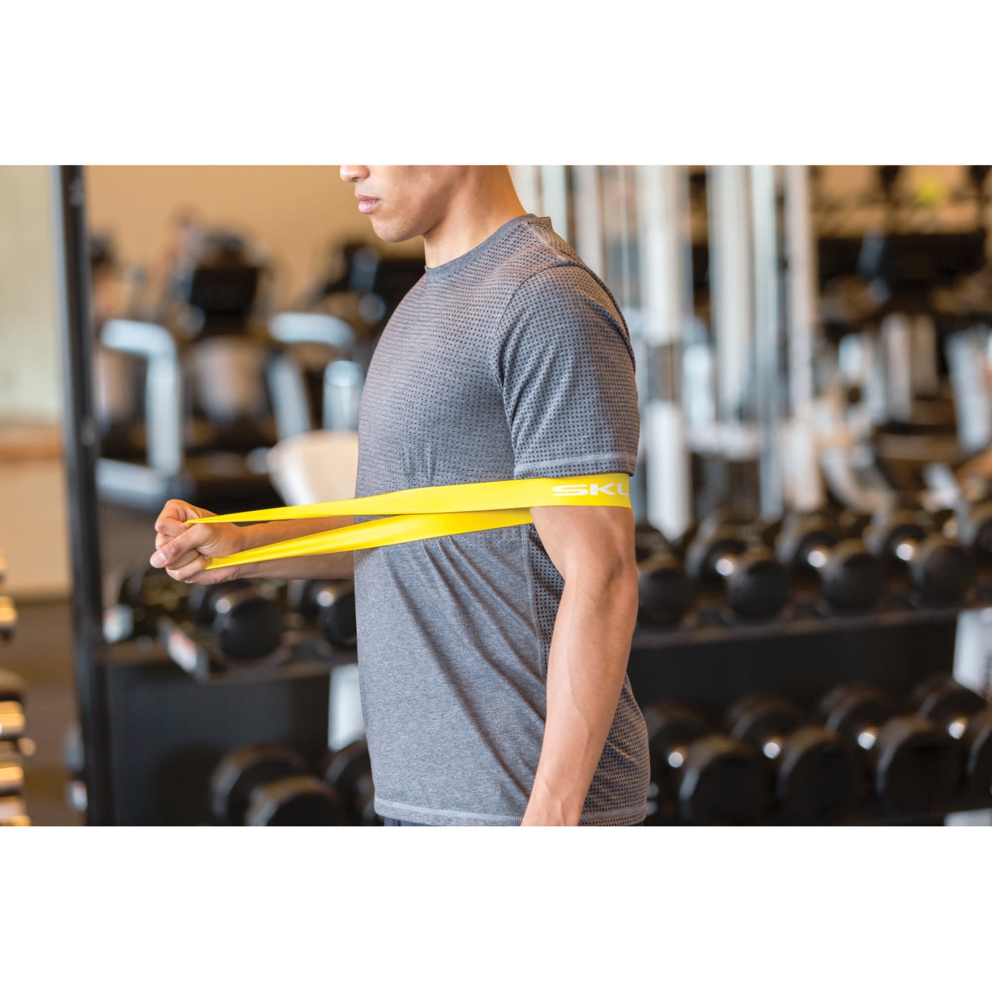 Man uses resistance band for arm exercise in a gym environment