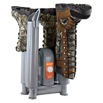 Camouflage boots dry in a portable drying device on a white background.