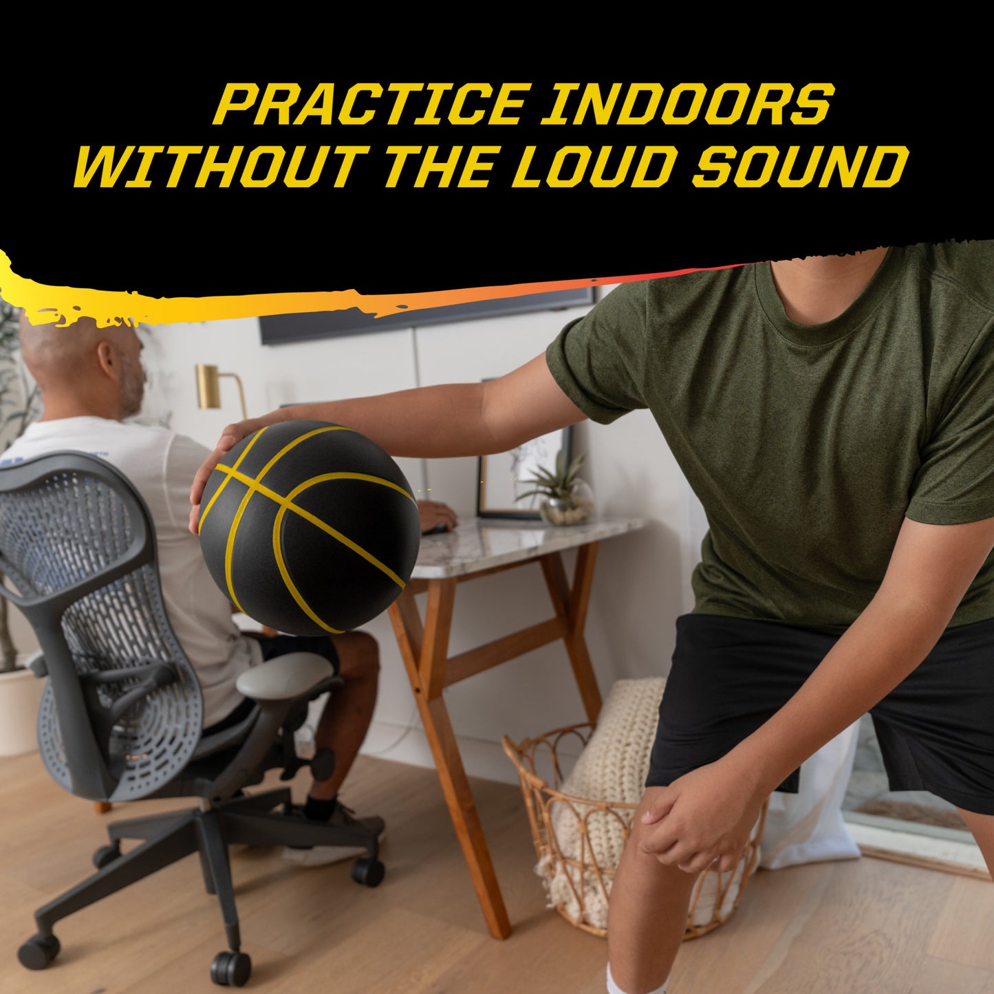 Person holds foam basketball while another works at desk in a home office.