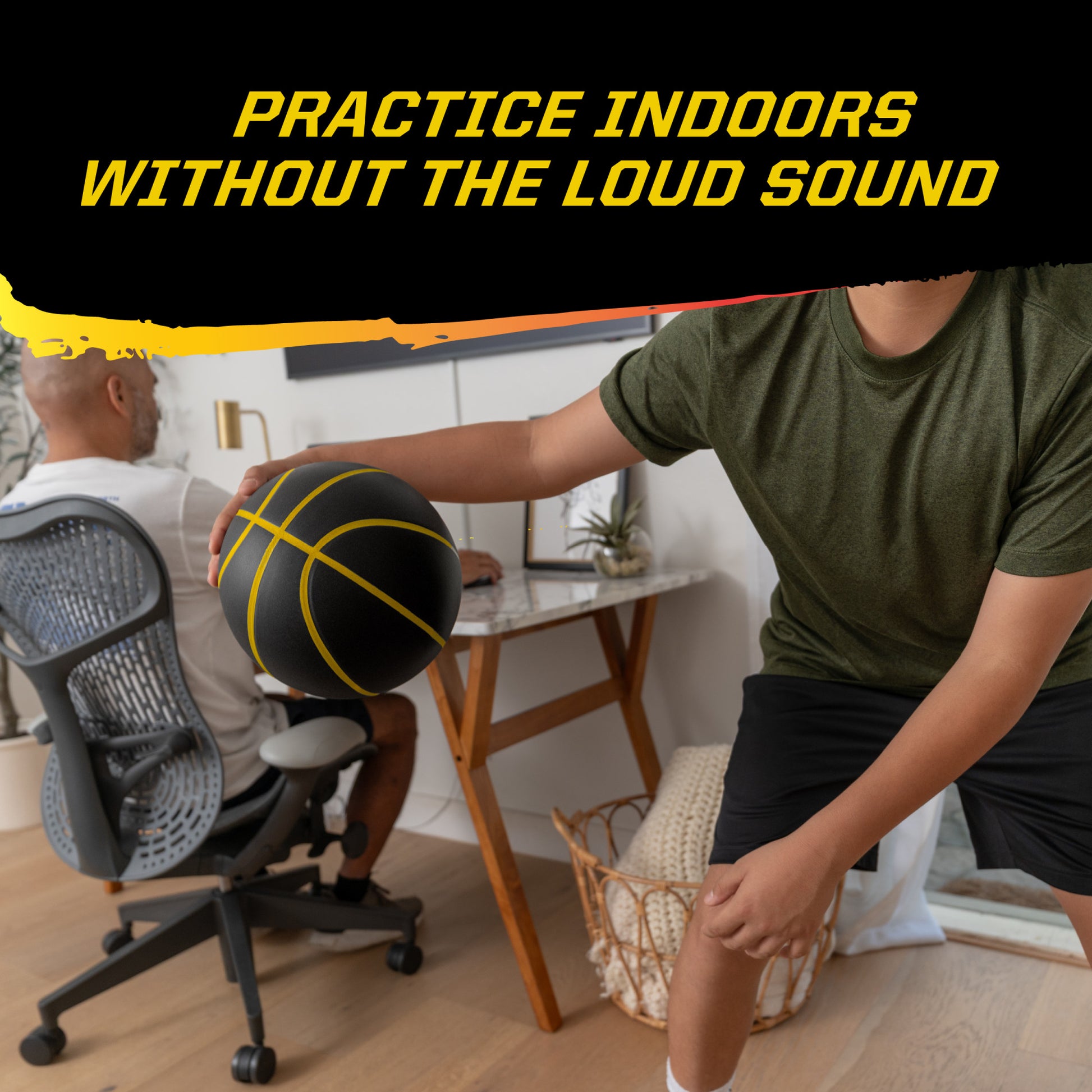 Person holds foam basketball while another works at desk in a home office.