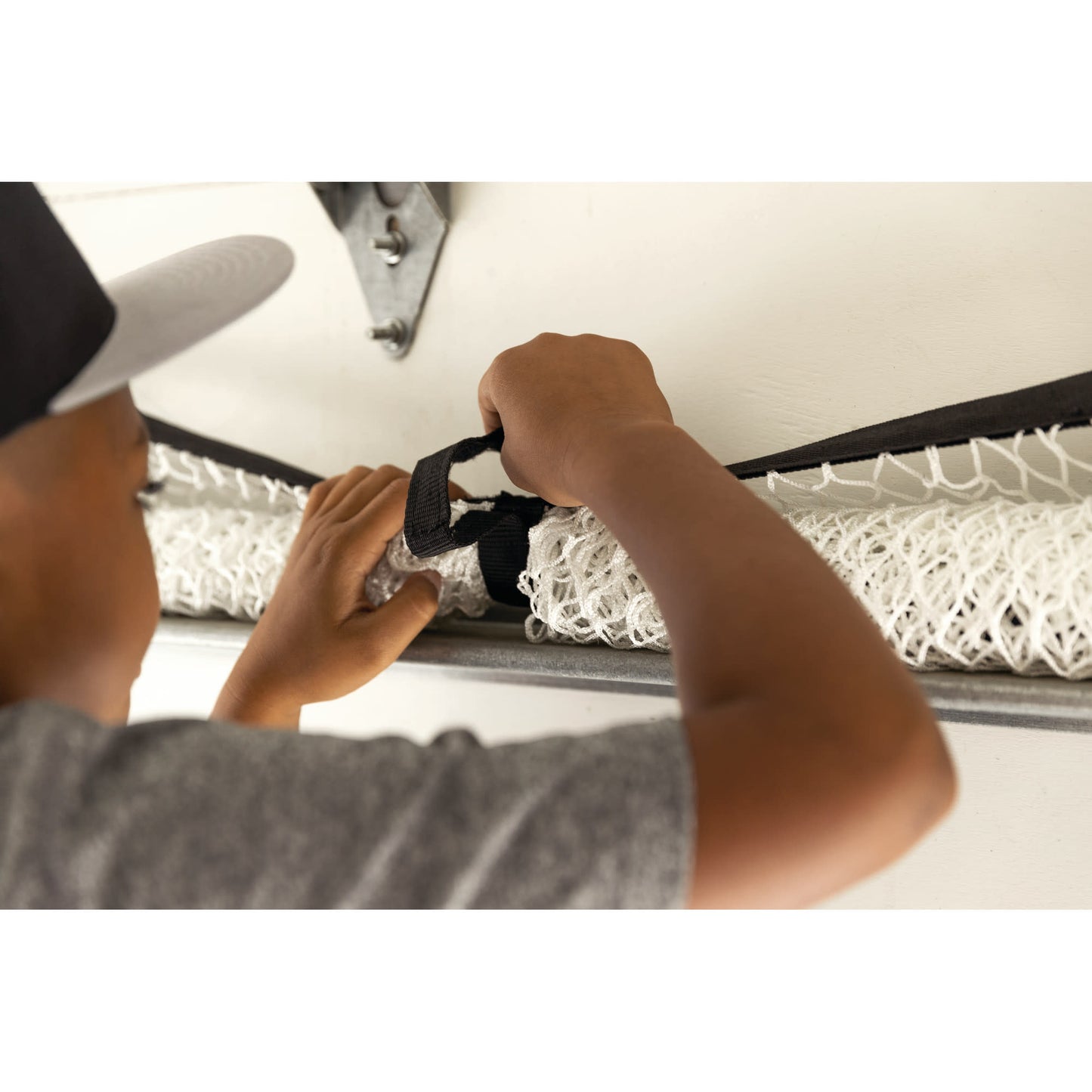 Child secures a mattress with a strap on a bed in a room