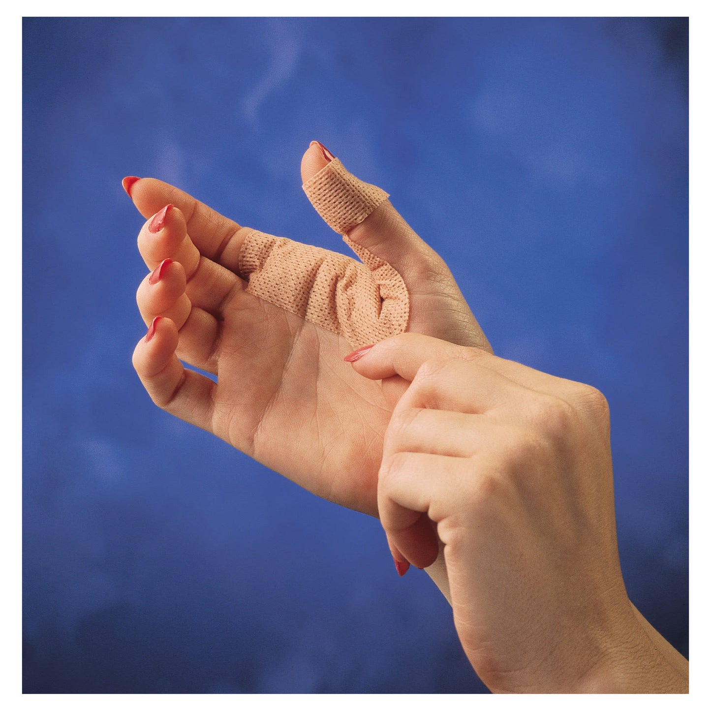 A hand with a bandaged thumb reaching for another hand against a blue sky background.
