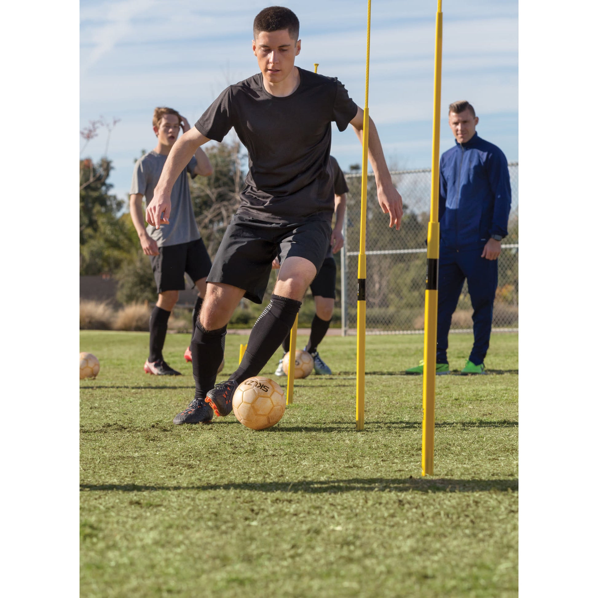Soccer player dribbles ball through training poles during a practice session outdoors