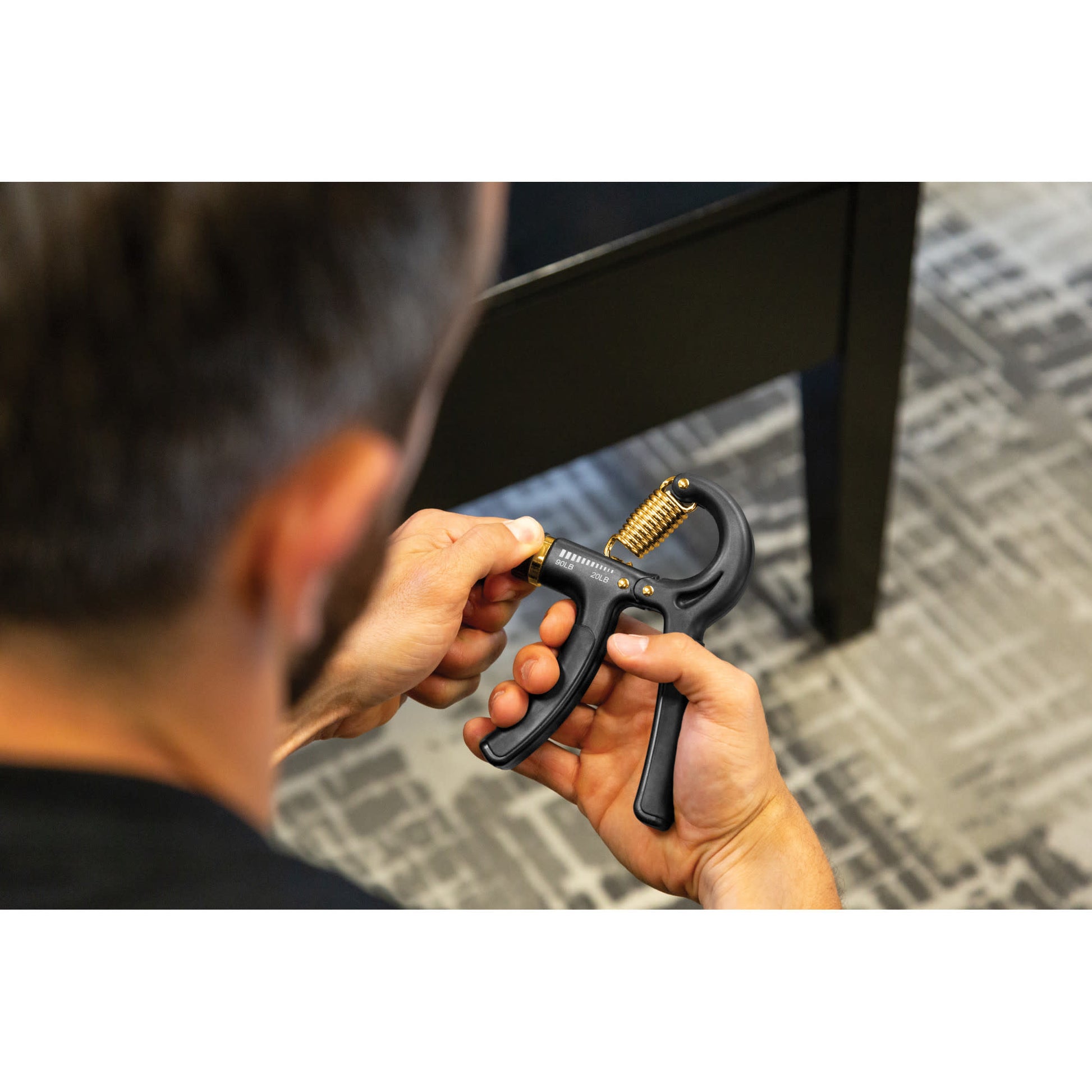 A person uses a handheld device to measure under a desk in an office setting