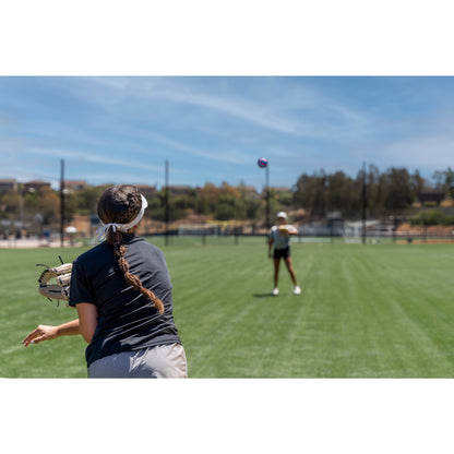 Girl catches a volleyball on a grassy field during outdoor sports practice